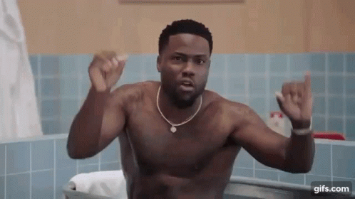 A Shirtless Man Is Taking A Bath In A Bathtub And Making A Funny Face . GIF