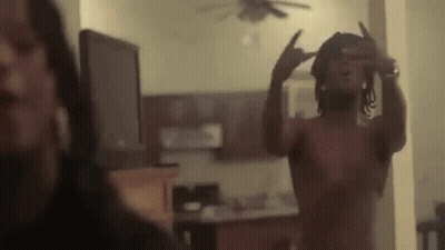 A Shirtless Man Is Taking A Picture Of Himself In A Mirror In A Living Room . GIF