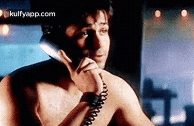 A Shirtless Man Is Talking On A Phone Without A Shirt On . GIF