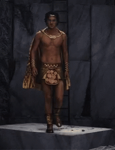 A Shirtless Man Is Wearing A Cape And A Necklace GIF