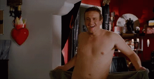 A Shirtless Man Is Wrapped In A Towel In A Room . GIF