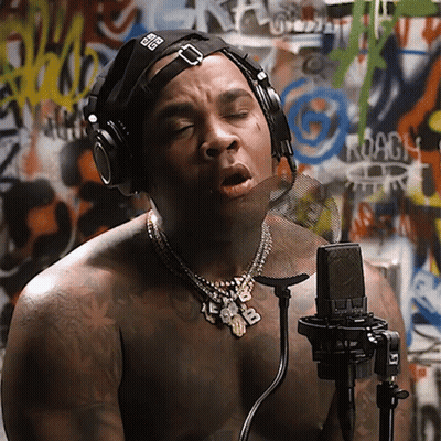 A Shirtless Man Singing Into A Microphone With Headphones On GIF
