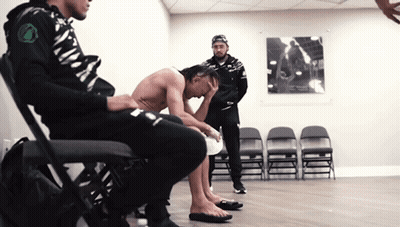 A Shirtless Man Sits On A Chair With His Head Down GIF