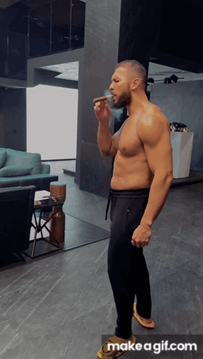A Shirtless Man Smoking A Cigar In A Living Room With Make A Gif.com On The Bottom GIF