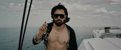 A Shirtless Man Smoking A Cigarette On A Boat With Sunny Music Written On The Bottom GIF