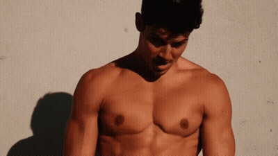 A Shirtless Man Standing In Front Of A Wall GIF