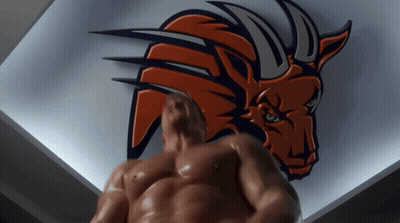 A Shirtless Man Stands In Front Of A Bull Logo On A Wall GIF
