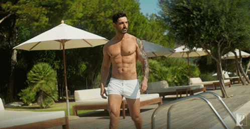 A Shirtless Man Stands In Front Of A Swimming Pool GIF