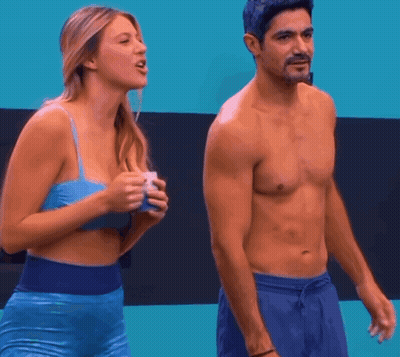 A Shirtless Man Stands Next To A Woman In A Blue Bra GIF