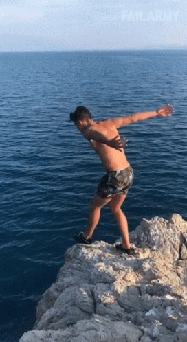 A Shirtless Man Stands On A Rocky Cliff Overlooking The Ocean With Failarmy Written On The Bottom GIF