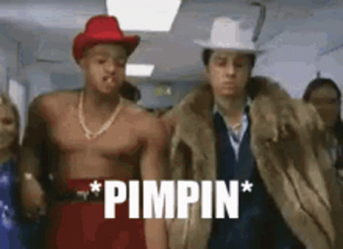 A Shirtless Man Wearing A Cowboy Hat And A Fur Coat Is Standing Next To Another Shirtless Man . GIF