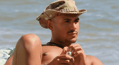 A Shirtless Man Wearing A Cowboy Hat Is Looking At His Phone GIF
