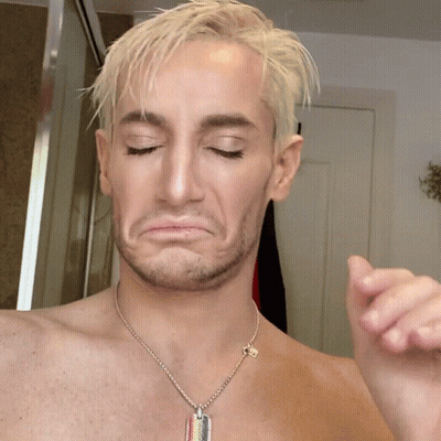 A Shirtless Man Wearing A Dog Tag Necklace Making A Face GIF