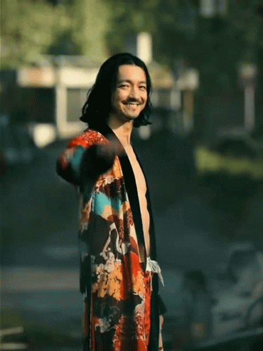 A Shirtless Man Wearing A Kimono Is Smiling And Waving GIF