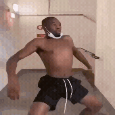 A Shirtless Man Wearing A Mask And Shorts Is Standing In A Hallway . GIF