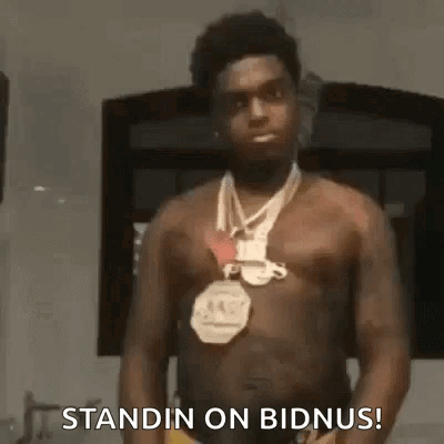 A Shirtless Man Wearing A Necklace And A Medal Around His Neck Is Standing In A Room . GIF