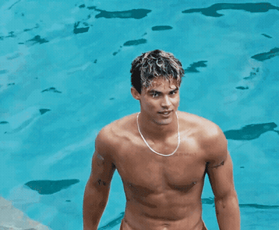 A Shirtless Man Wearing A Necklace Stands In Front Of A Pool GIF