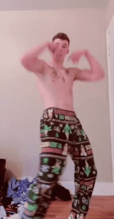 A Shirtless Man Wearing A Pair Of Christmas Pajamas GIF