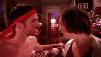 A Shirtless Man Wearing A Red Headband Is Fighting A Woman In A Bedroom . GIF