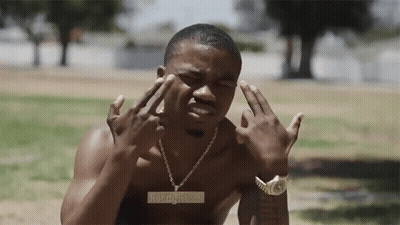 A Shirtless Man Wearing A Watch And A Necklace With A Pendant That Says ' Aboogy.com ' GIF
