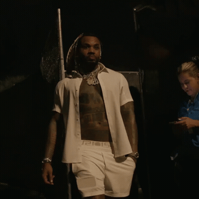 A Shirtless Man Wearing A White Shirt With A Greek Key Pattern On The Sleeves GIF