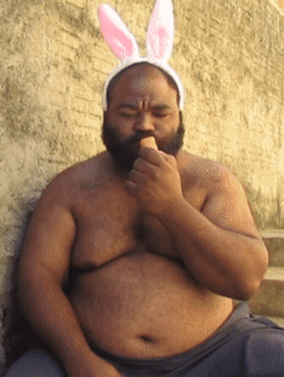 A Shirtless Man Wearing Bunny Ears Is Eating An Ice Cream GIF