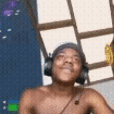 A Shirtless Man Wearing Headphones And A Beanie Is Smiling . GIF