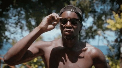 A Shirtless Man Wearing Sunglasses And A Black Hat GIF