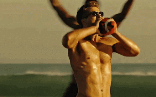 A Shirtless Man Wearing Sunglasses Is Holding A Football In His Hands GIF