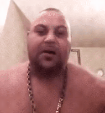 A Shirtless Man With A Beard And A Chain Around His Neck Is Talking To The Camera . GIF