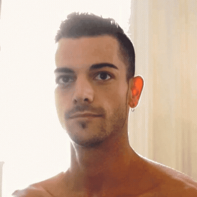 A Shirtless Man With A Beard And Earrings On His Ears GIF