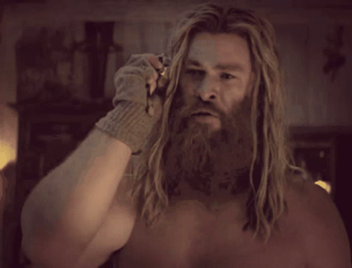 A Shirtless Man With A Beard And Long Hair Is Wearing A Glove . GIF