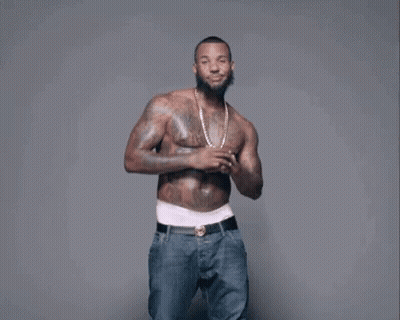 A Shirtless Man With A Beard And Tattoos Is Dancing . GIF