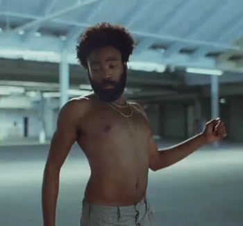 A Shirtless Man With A Beard Is Dancing In A Parking Garage GIF