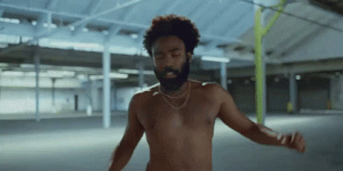 A Shirtless Man With A Beard Is Dancing In A Room GIF