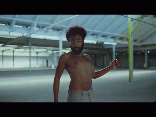 A Shirtless Man With A Beard Is Dancing In An Empty Room GIF