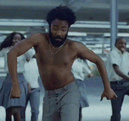 A Shirtless Man With A Beard Is Dancing With A Group Of People GIF