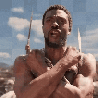 A Shirtless Man With A Beard Is Holding A Spear In His Hand And Making A Funny Face . GIF