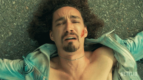 A Shirtless Man With A Beard Is Laying On The Ground With A Netflix Logo Behind Him GIF