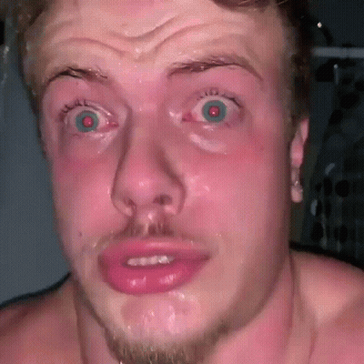A Shirtless Man With A Beard Is Making A Funny Face With His Mouth Open And His Eyes Wide Open . GIF