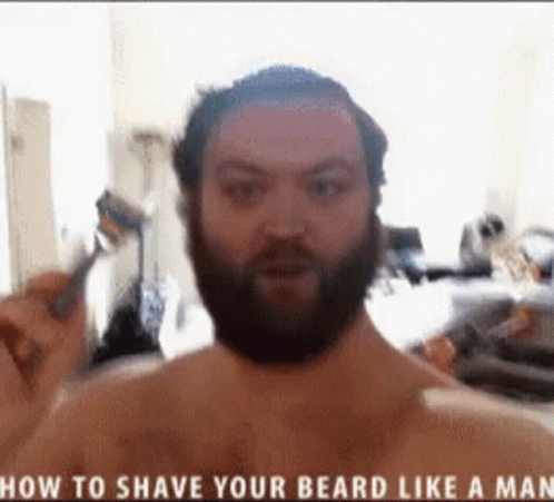 A Shirtless Man With A Beard Is Shaving Himself GIF
