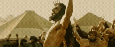 A Shirtless Man With A Beard Is Standing In Front Of A Crowd Of People . GIF