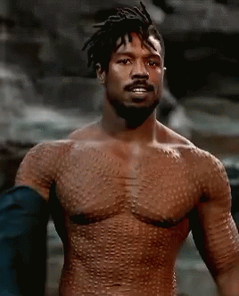 A Shirtless Man With A Beard Is Standing In Front Of A Rock Wall . GIF