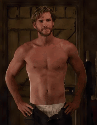A Shirtless Man With A Beard Is Standing With His Hands On His Hips . GIF