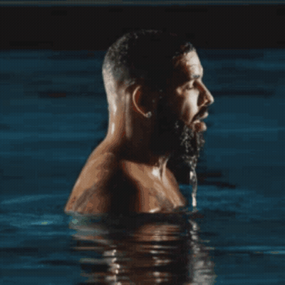 A Shirtless Man With A Beard Is Swimming In A Pool . GIF