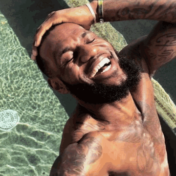 A Shirtless Man With A Beard Is Taking A Selfie With His Hand On His Head GIF