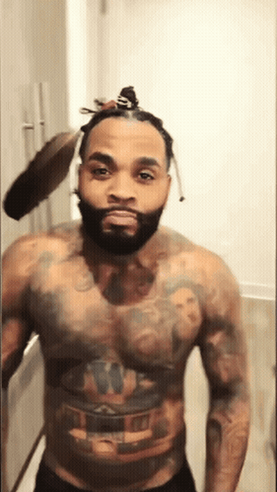 A Shirtless Man With A Bun On His Head Has A Tattoo On His Chest GIF