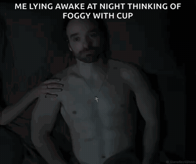A Shirtless Man With A Cross Necklace Is Laying In The Dark GIF