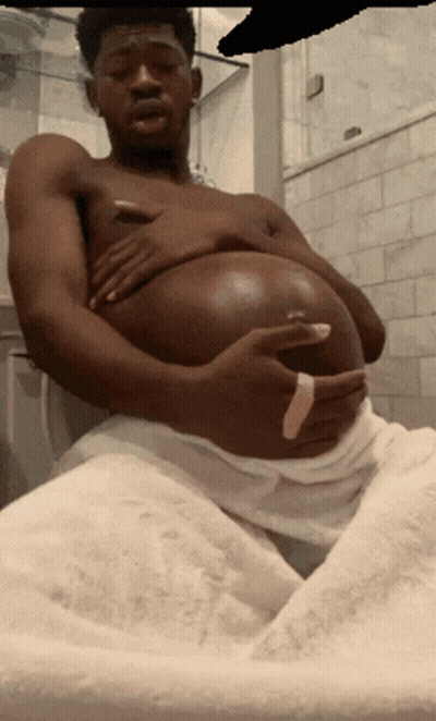 A Shirtless Man With A Large Belly Is Sitting In A Bathroom GIF