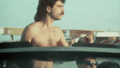 A Shirtless Man With A Mustache Is Driving A Car .. GIF